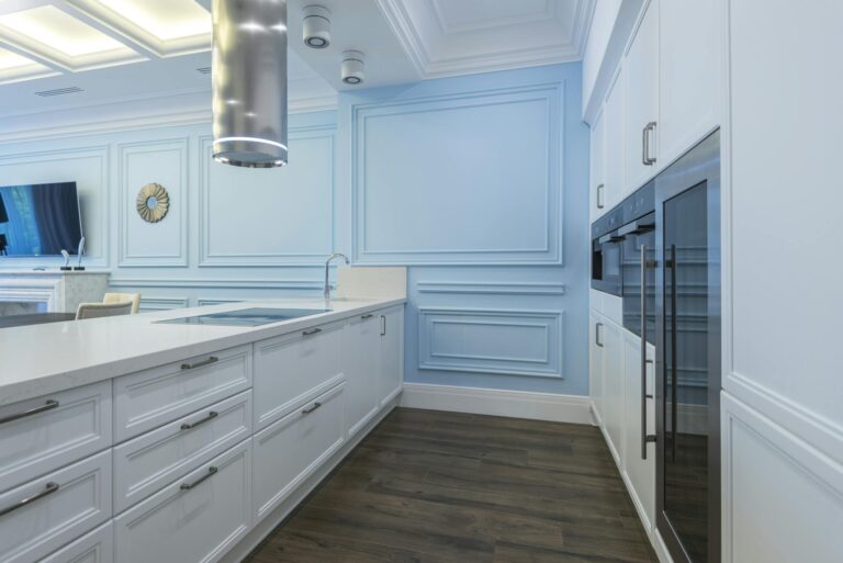 Contemporary kitchen with blue panel walls and sleek white cabinets.