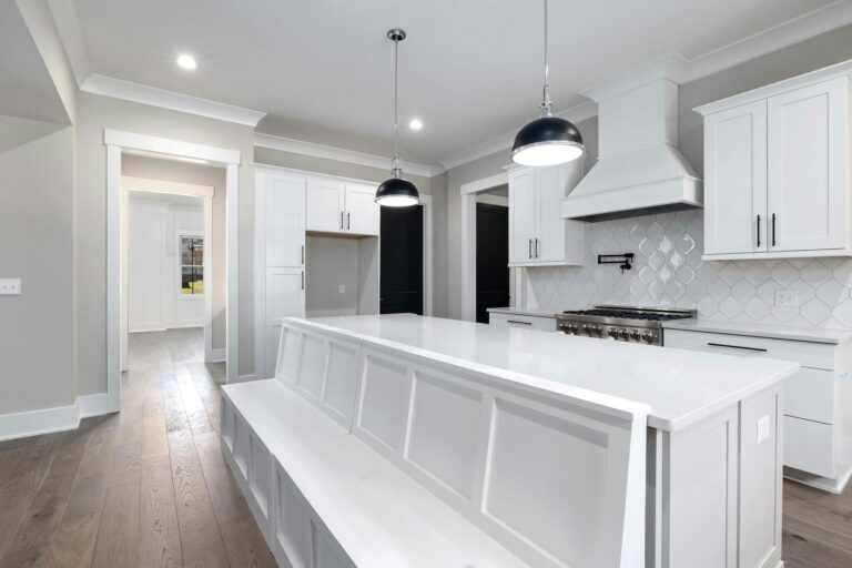 Sleek white kitchen with modern furniture and elegant lighting fixtures.