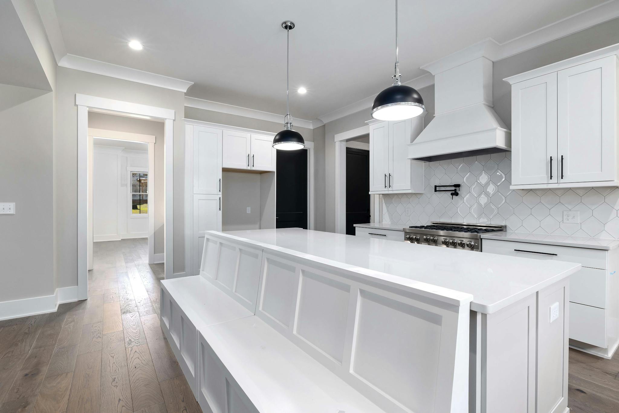 Sleek white kitchen with modern furniture and elegant lighting fixtures.